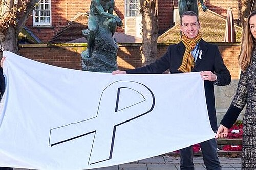 Peter Aga and Amanda hold up the white ribbon flag